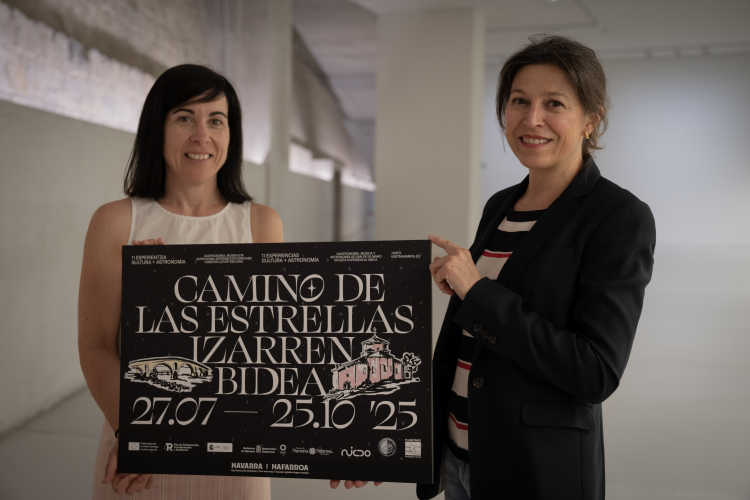 Fotografía de Ana Rivas, directora general de Cultura, con la representante de la empresa pública NICDO, con el cartel de Camino de las Estrellas / Izarren Bidea