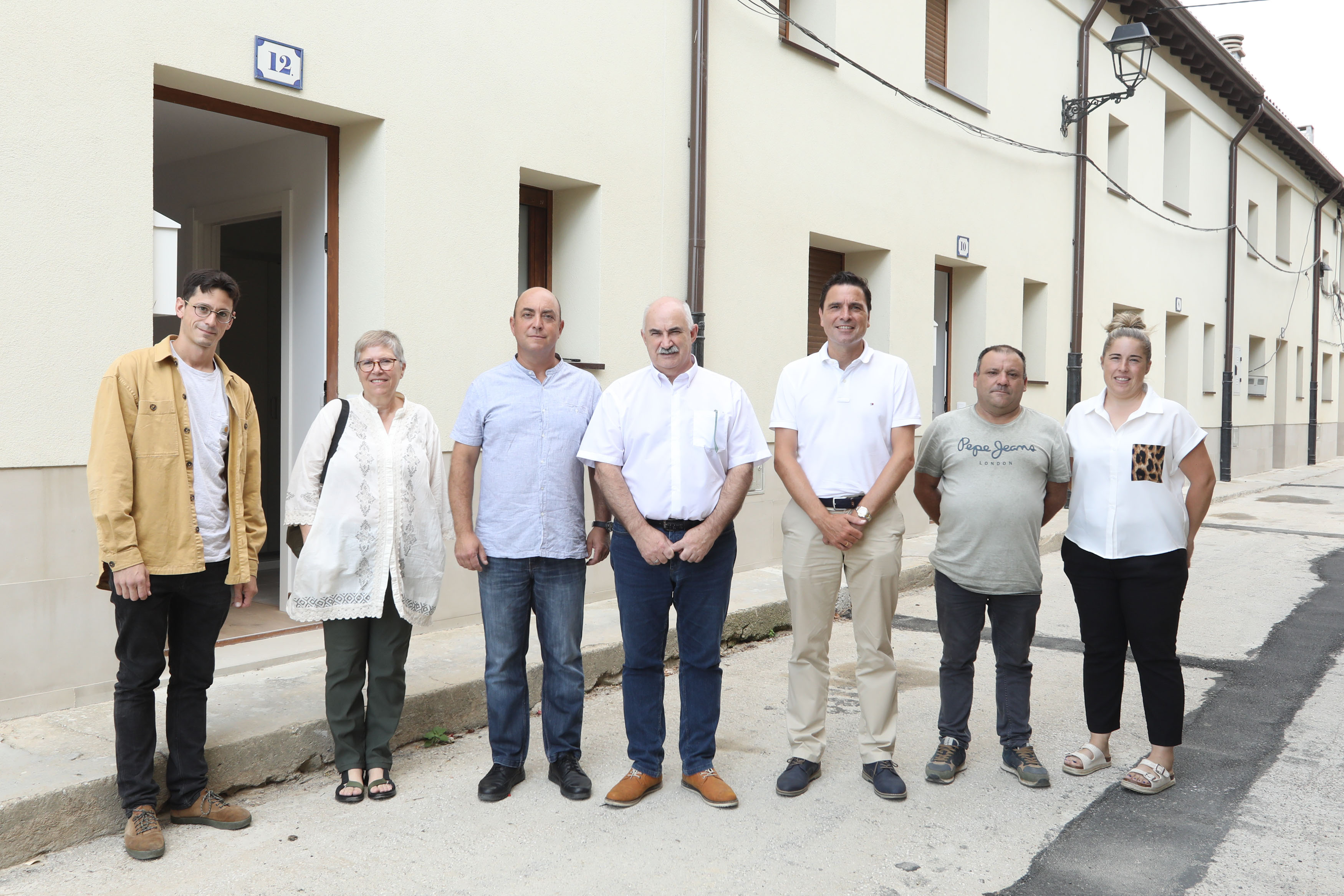 Fotografía de varias personas de pie delante de las viviendas rehabilitadas