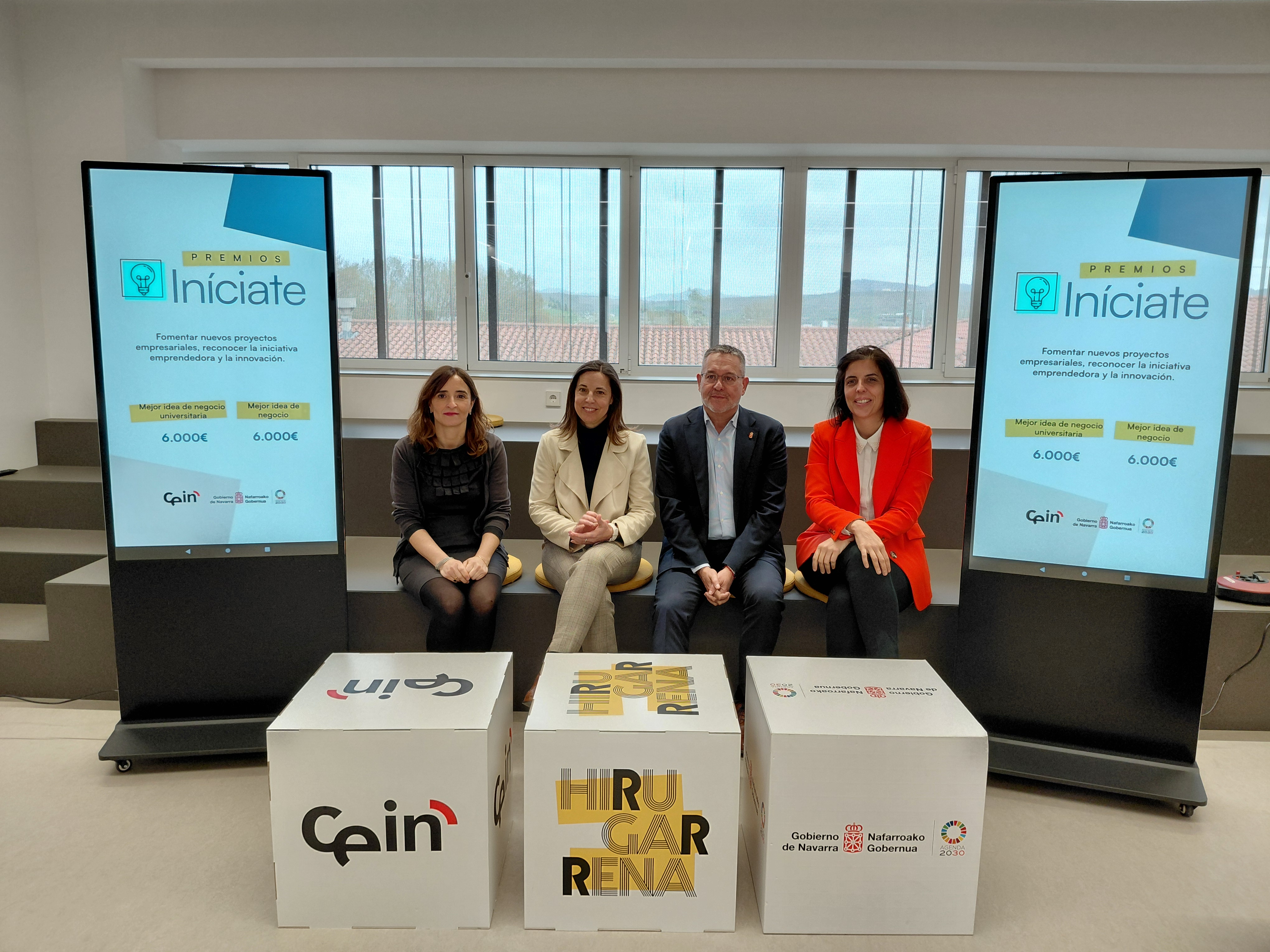 Cuatro personas posando delante de unos cubos con logos