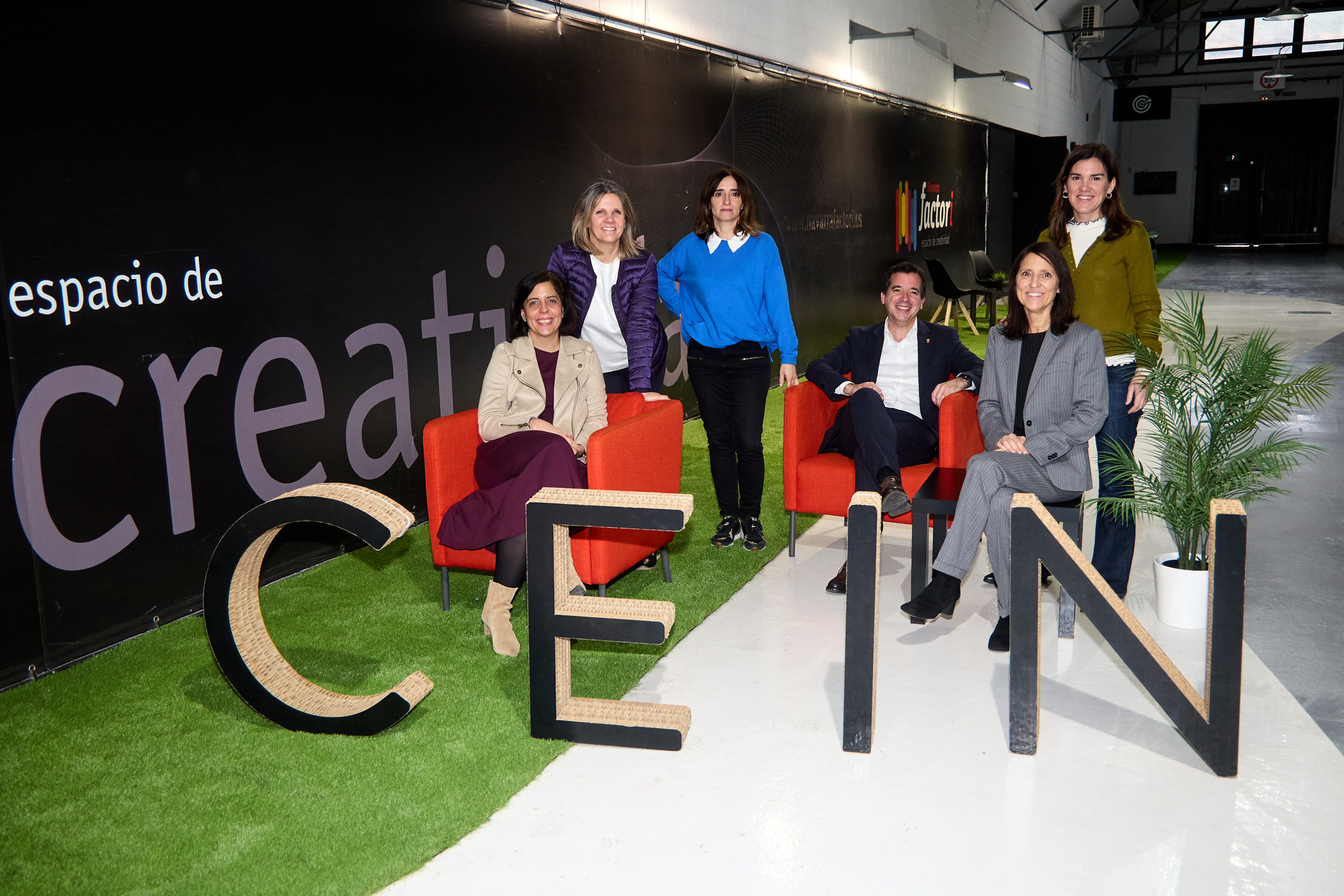 Miembros de CEIN posando detrás del logo del mismo