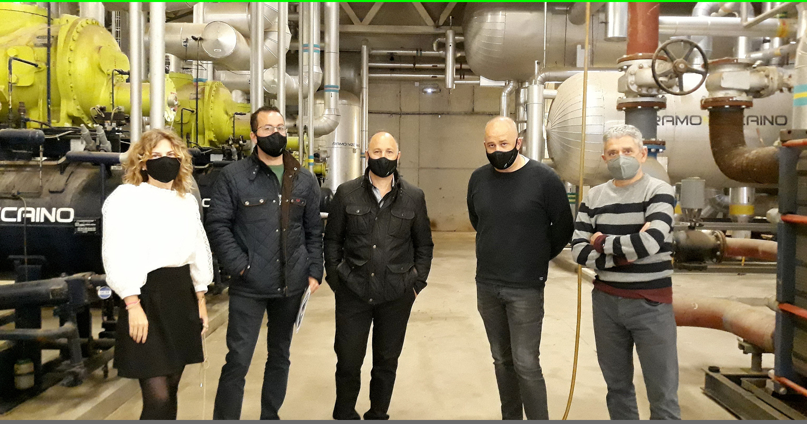 Fotografía de cuatro hombres y una mujer dentro de una nave industrial.