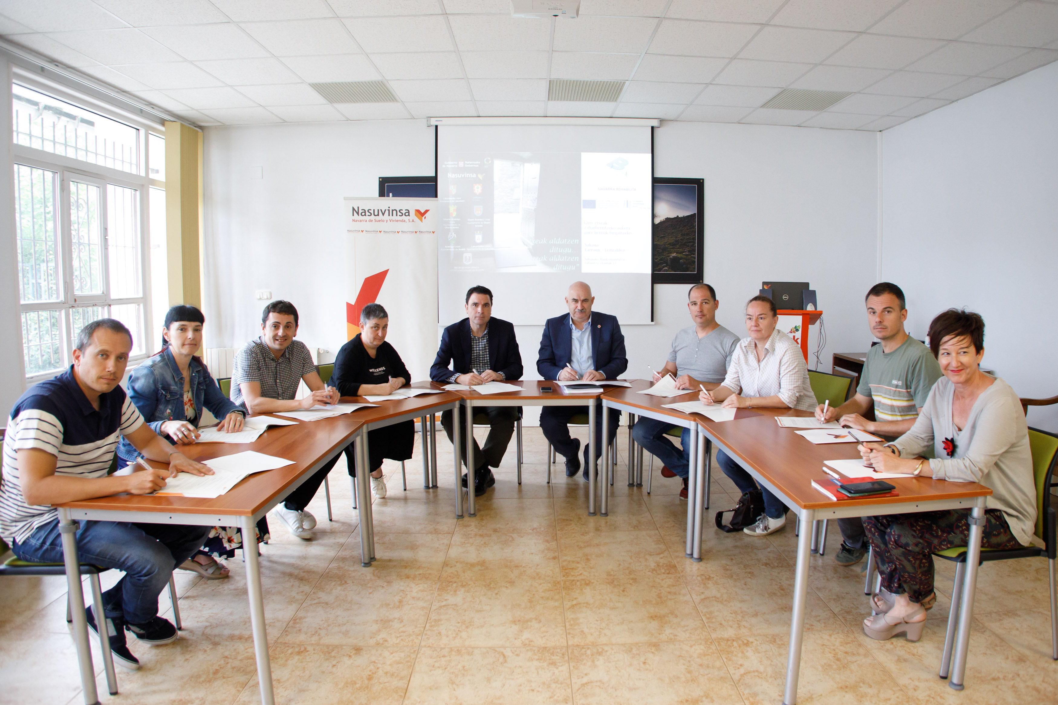 Fotografía interior de un momento de la firma del convenio donde aparecen varias personas sentadas alrededor de una mesa.