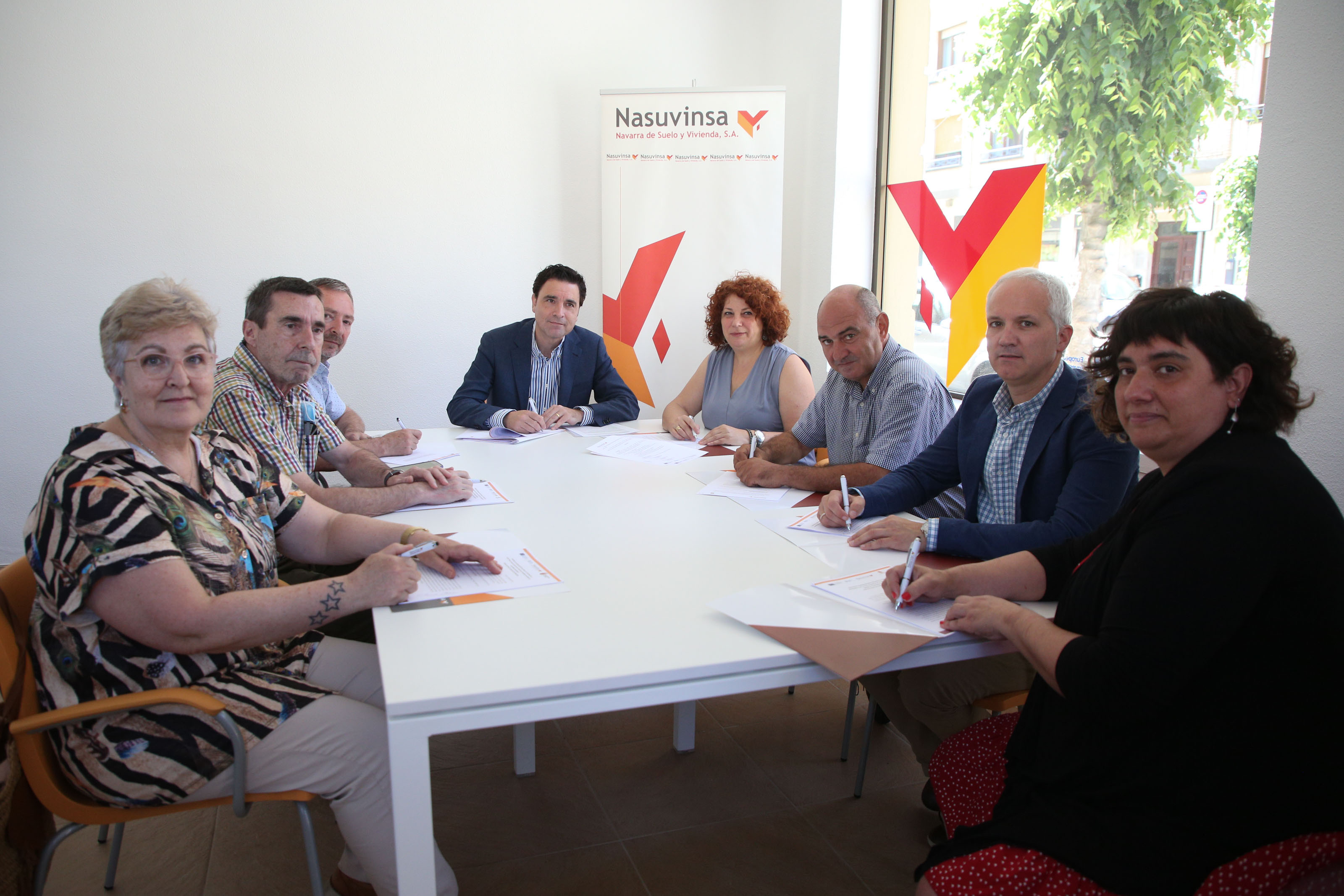 Fotografía de varias personas sentadas en una mesa mientras firman el convenio. 