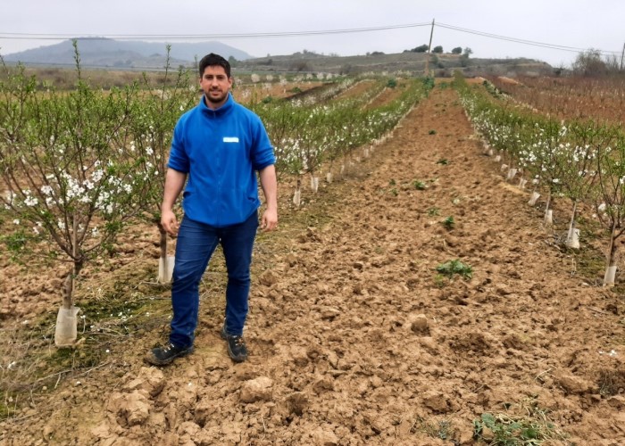 Carlos Marzo, a la izquierda de la imagen con ropa de trabajo de color azul, con la finca experimental de Cadreita como fondo