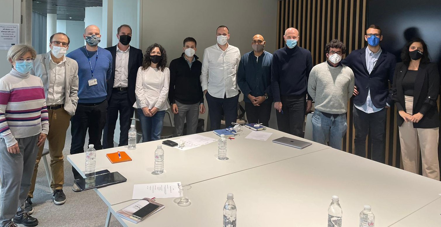 Fotografía de doce personas de pie en una sala de reuniones.