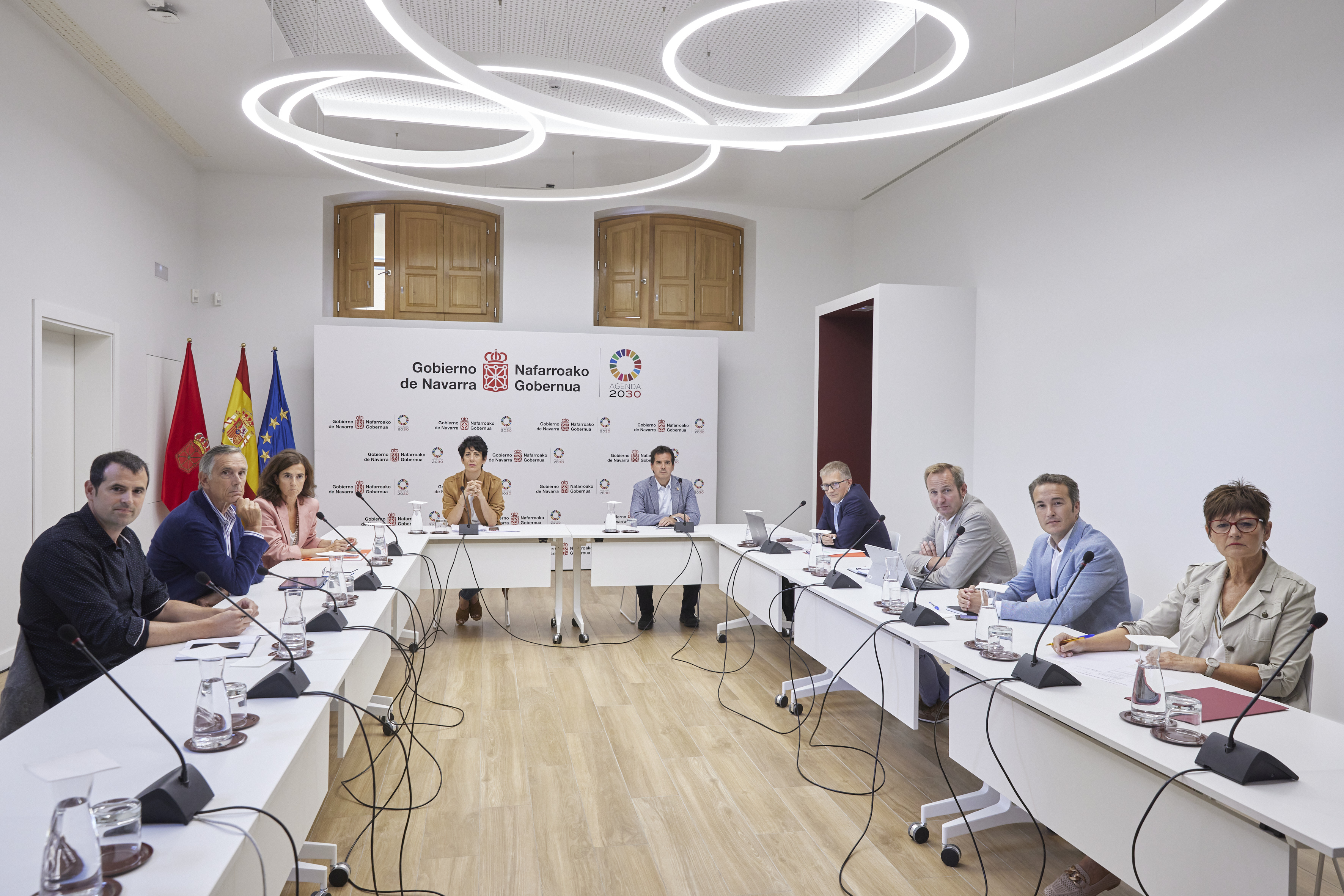 Fotografía de todos los miembros del Consejo de Administración sentados en forma de U mirando a cámara. En el fondo, Elma Saiz preside la reunión. A su lado, el consejero Mikel Irujo.