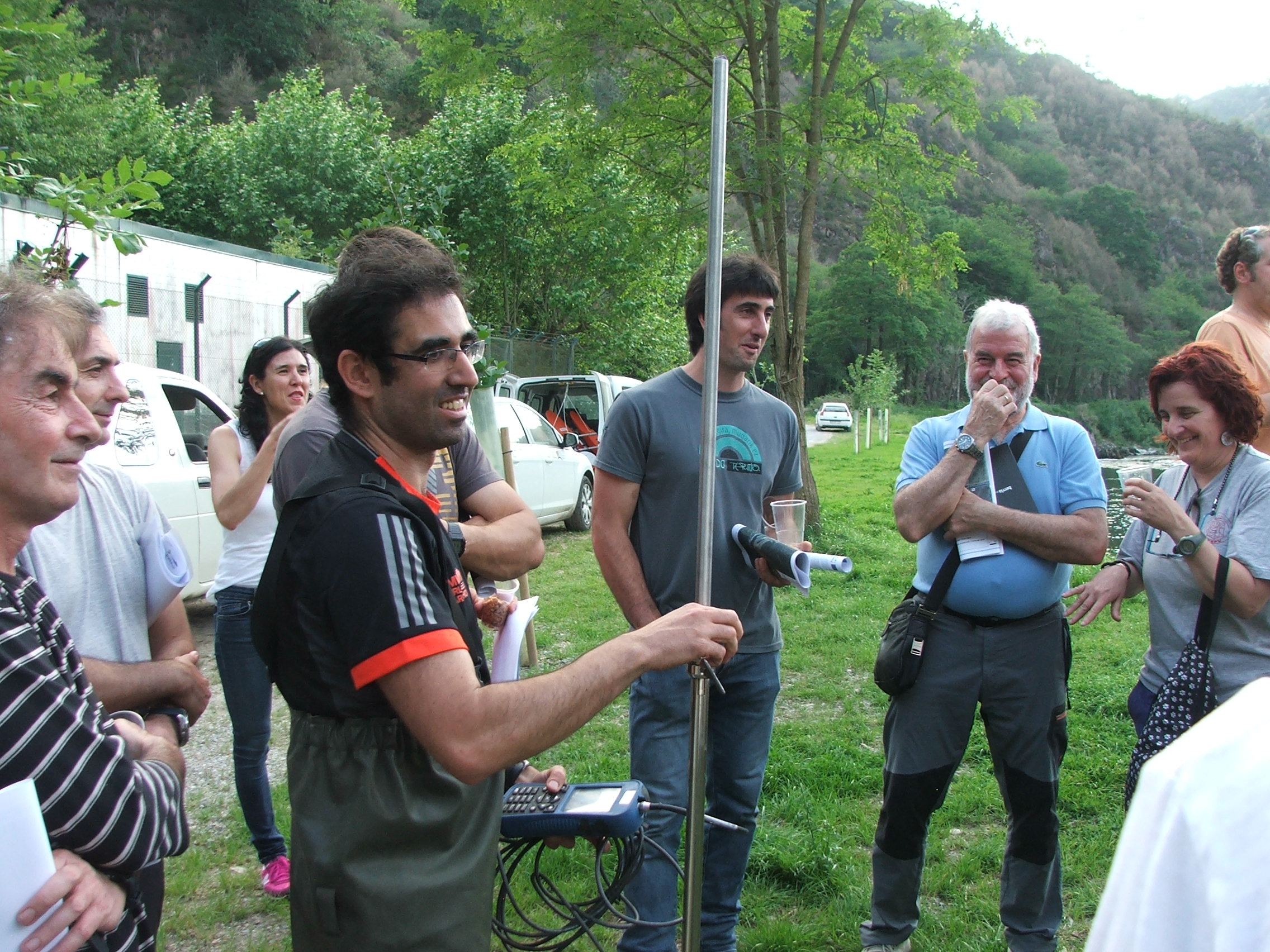 Varias personas atienden las explicaciones de un técnico en una visita de campo. Uno de ellos sostiene en la mano un aparato de medición.
