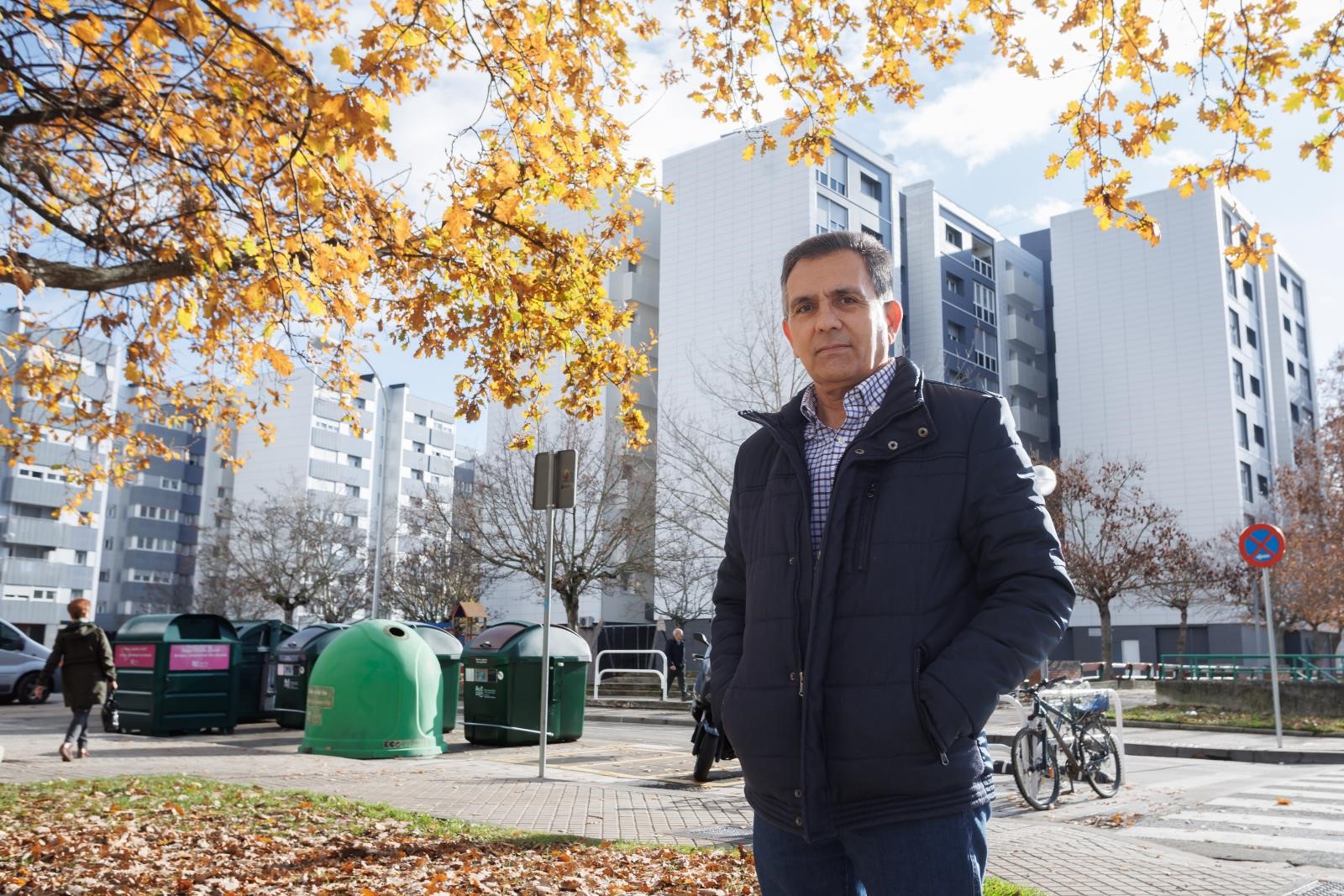 Fotografía de un hombre con varios edificios de viviendas rehabilitados detrás