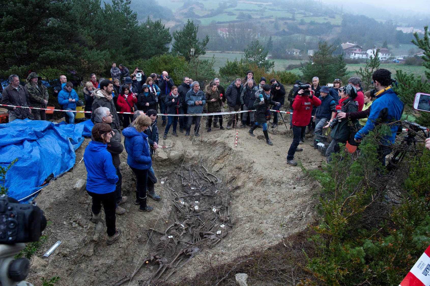 Fotografía de grupo tomada en el lugar donde se ve una fosa con los respectivos huesos