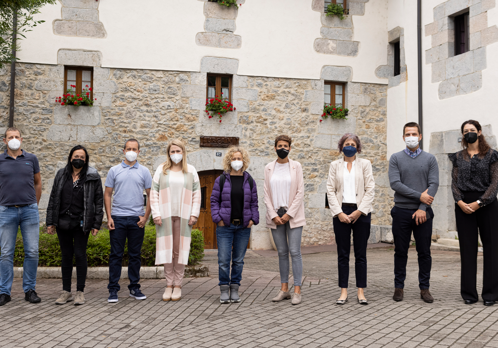 Fotografía de nueve personas delante de una casa de piedra