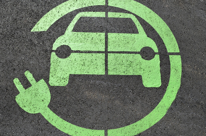 Fotografía de un coche y un enchufe de color verde pintado sobre una superficie negra