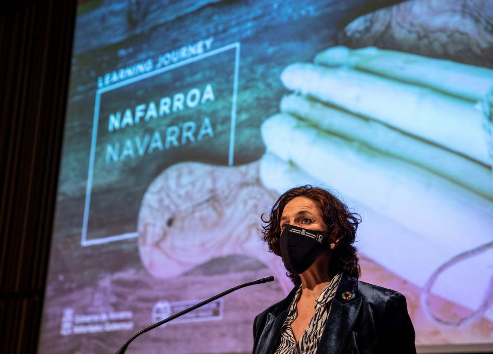 Fotografía de la consejera durante su intervención, de pie frente a un micrófono.