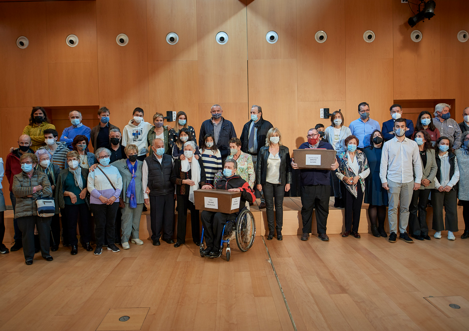 Fotografía de interior con varias personas de pie subidas encima de un escenario.