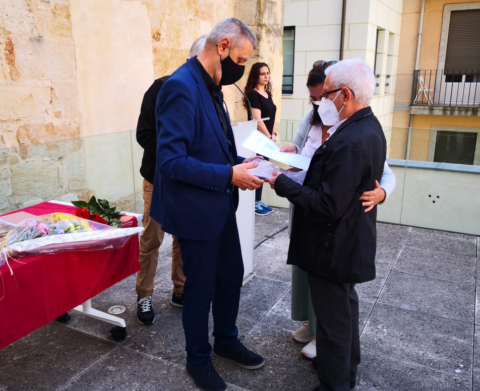 Fotografía exterior donde aparece un hombre dando un documento a otro