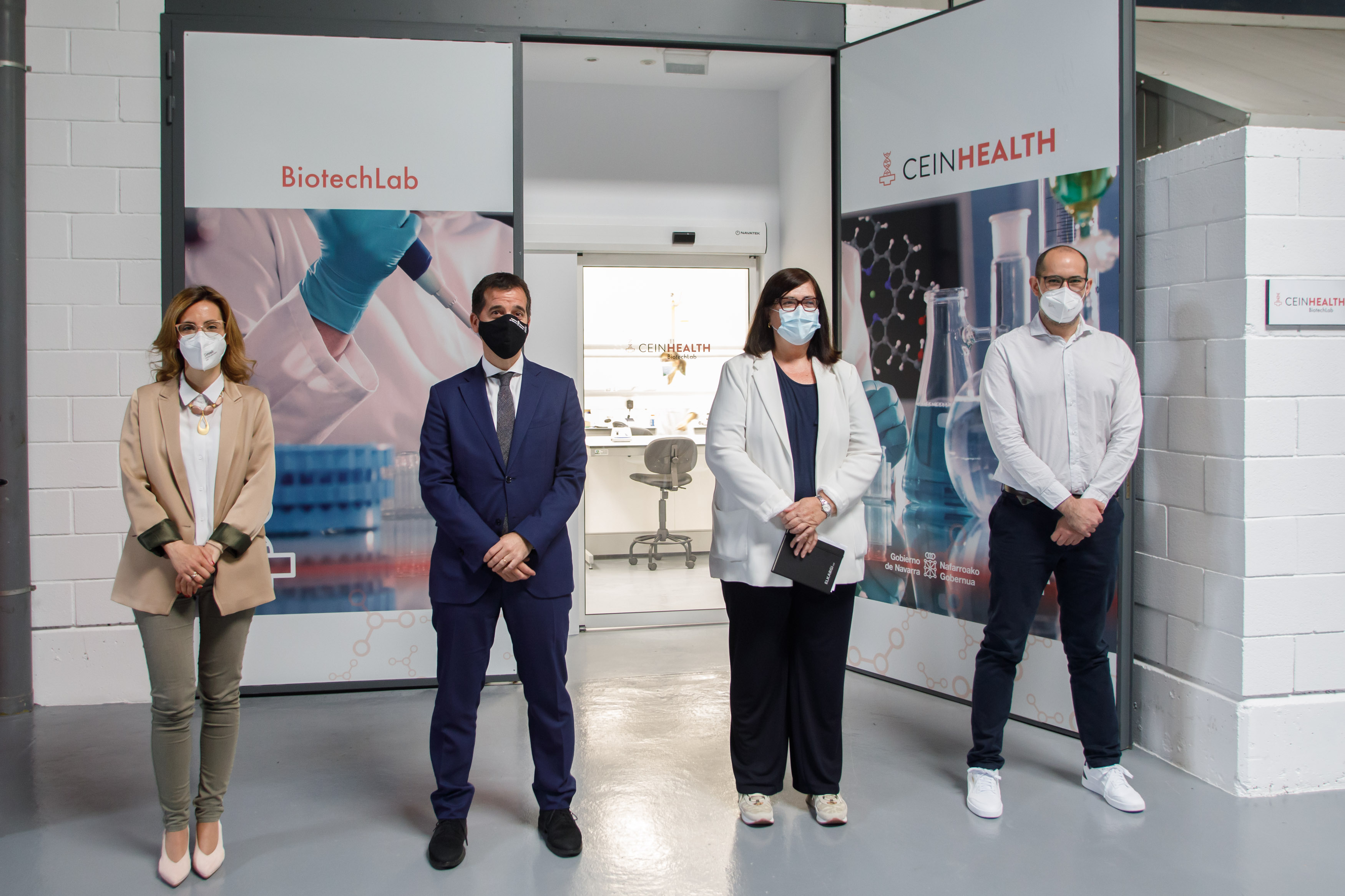 Fotografía interior con dos hombres y dos mujeres de pie a la entrada del laboratorio.