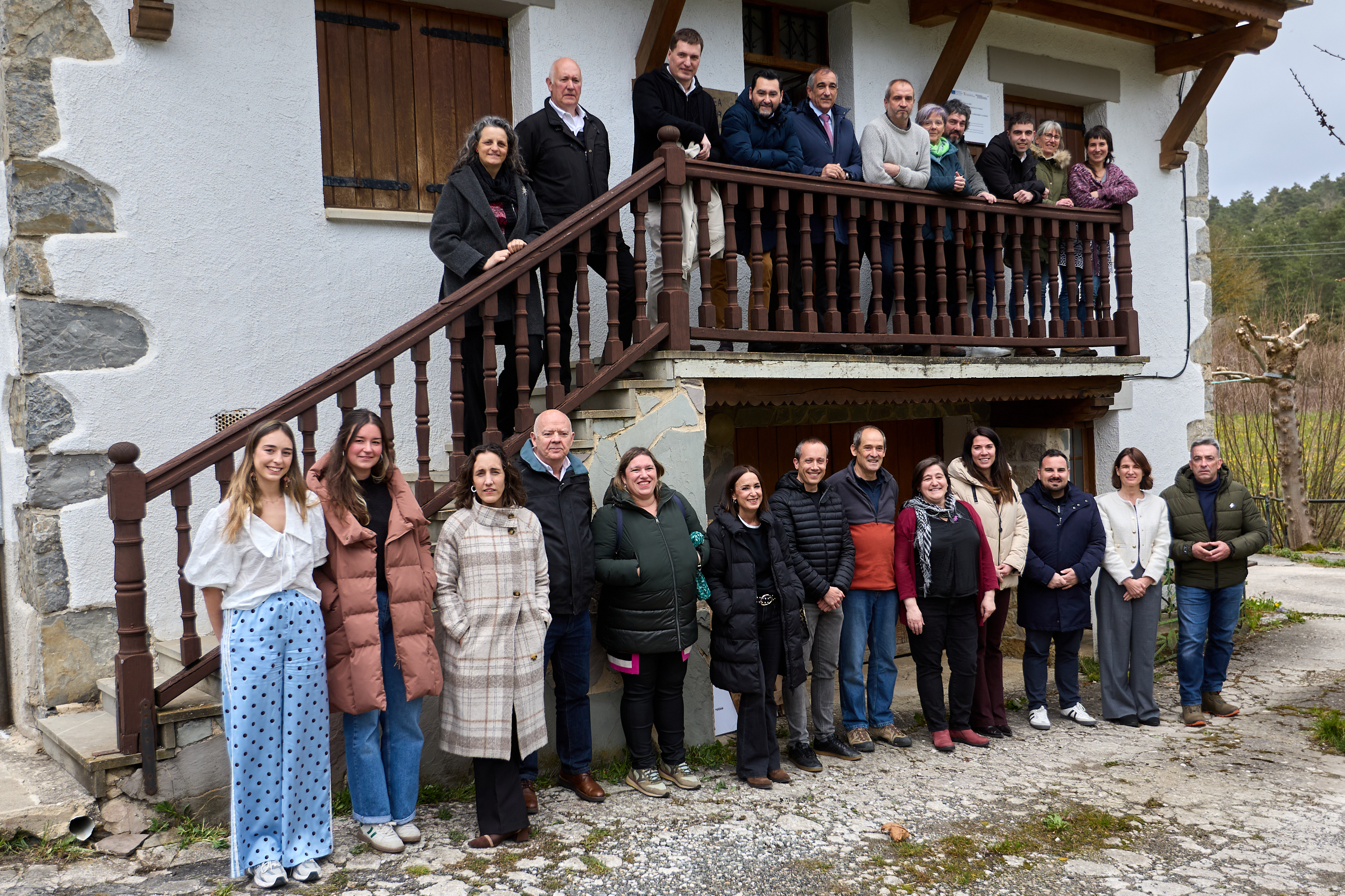 Un grupo de personas posando en la fachada de una casa y en sus escaleras
