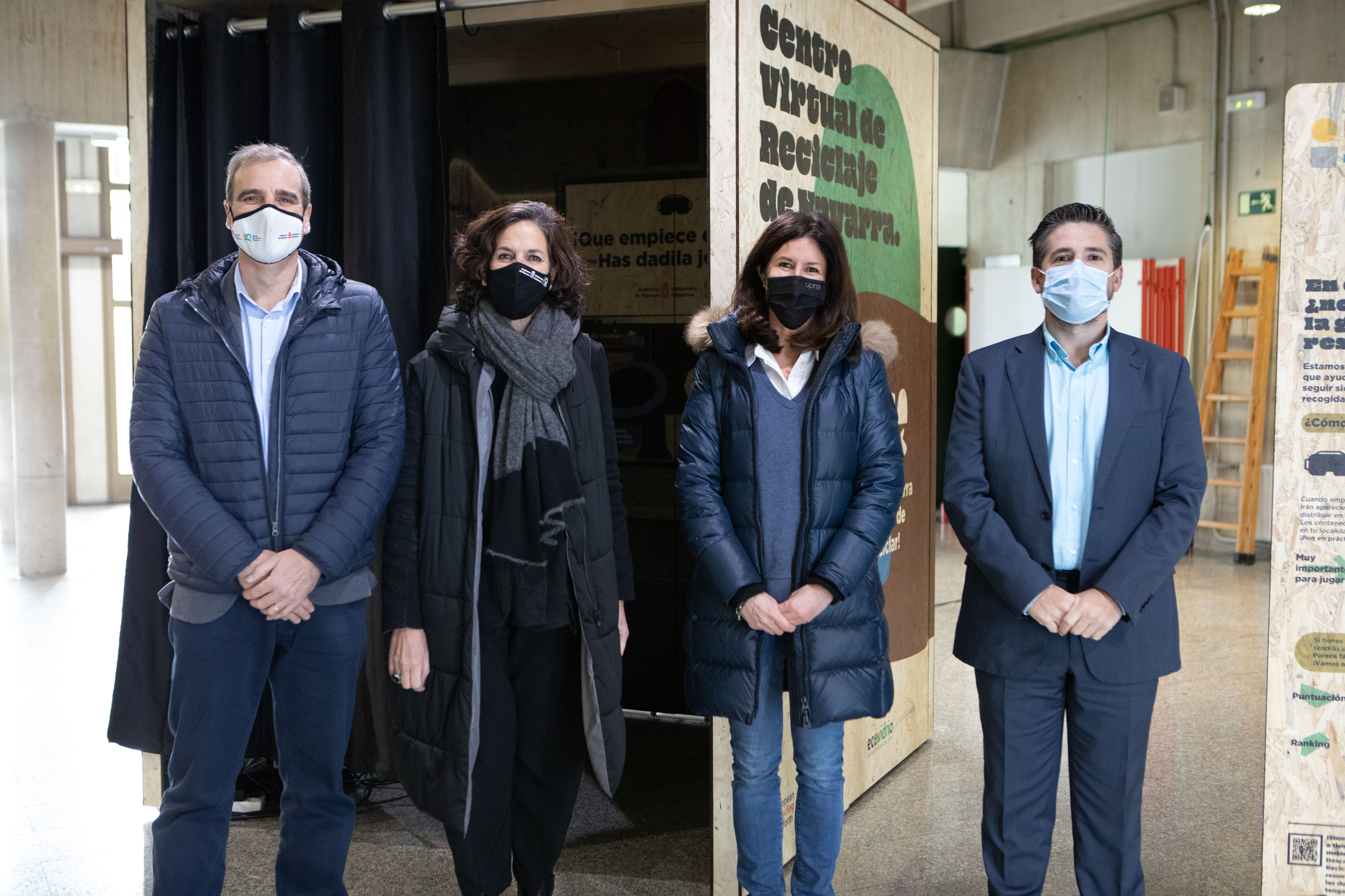 Fotografía de dos mujeres y dos hombres de pie con un panel informativo del juego.