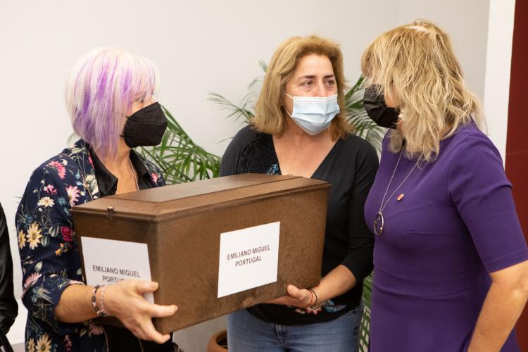 Fotografía de tres mujeres de pie y dos de ellas sujetando una caja