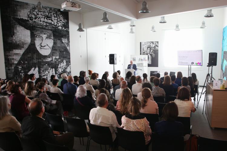 Fotografía de la presentación del festival, en la que aparecen muchas personas sentadas y en el atril el vicepresidente hablando de pie