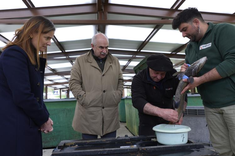 Dos visitantes junto con dos trabajadores y una trucha 