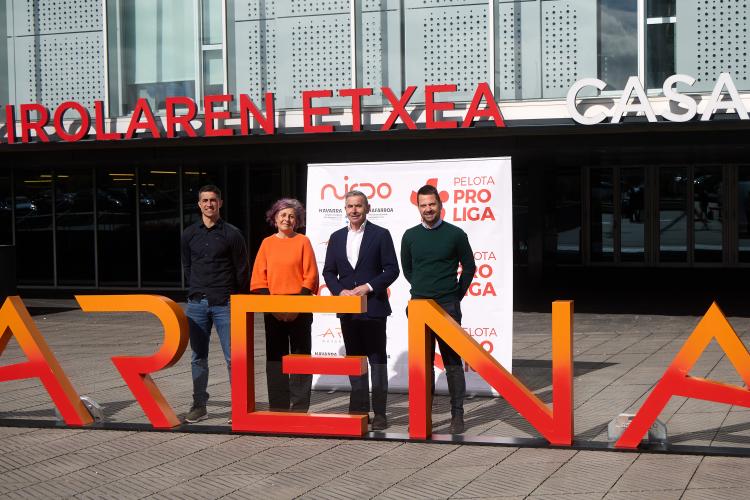 Cuatro personas posando delante del Navarra Arena con los logos