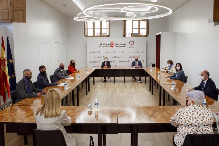 Fotografía de un momento de la reunión con los asistentes sentados en una mesa.