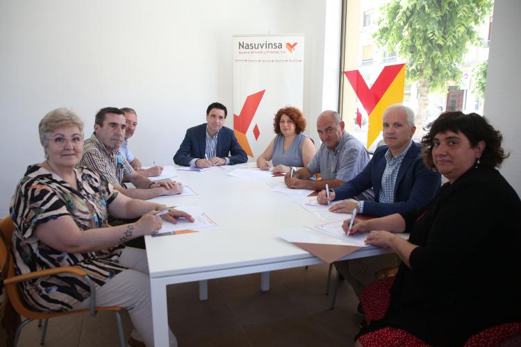 Fotografía de varias personas sentadas en una mesa mientras firman el convenio. 