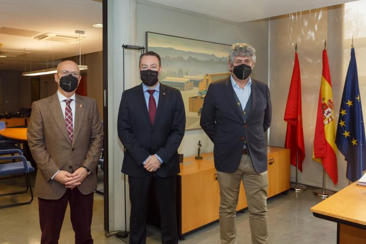 Fotografía de tres hombres de pié en un despacho.