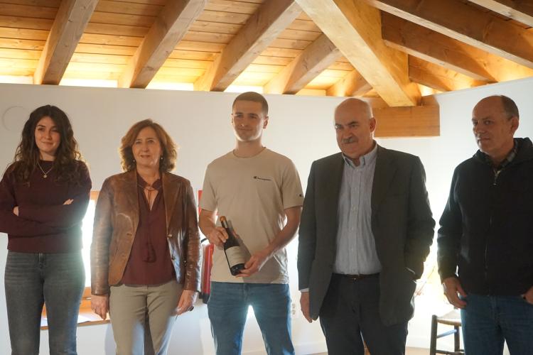 4 personas posando junto con una botella de vino