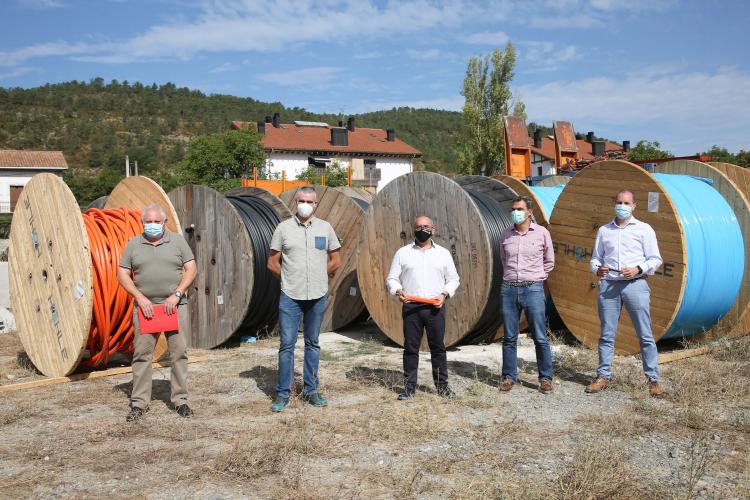 Fotografía exterior de cinco hombres de pie ante las bobinas de canalización para la fibra óptica