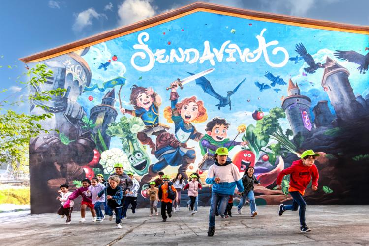Niños corriendo delante de un mural de Sendaviva