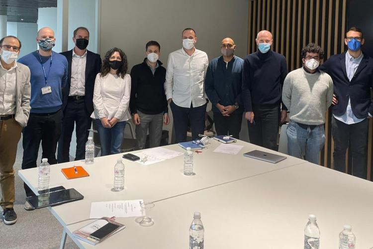 Fotografía de doce personas de pie en una sala de reuniones.