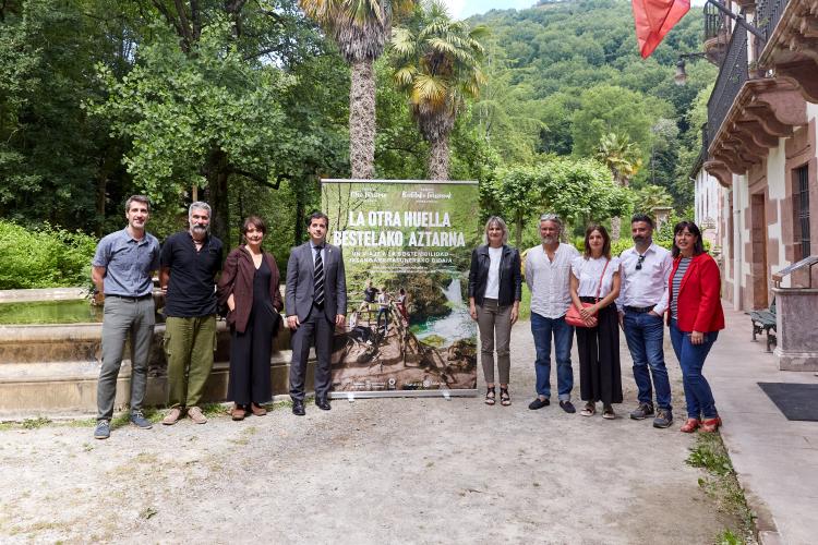 Fotografía de nueve personas que posan con el cartel que presenta el documental. 