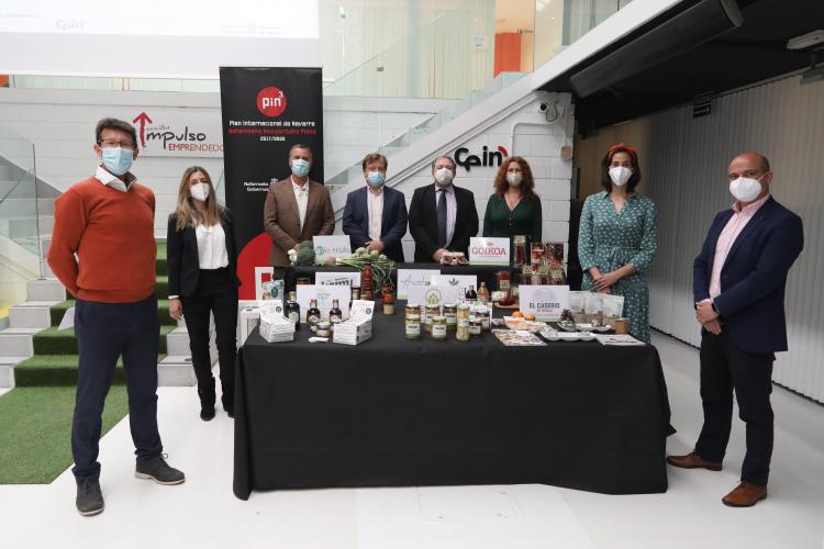 Fotografía de ocho personas alrededor de una mesa con productos alimentarios.