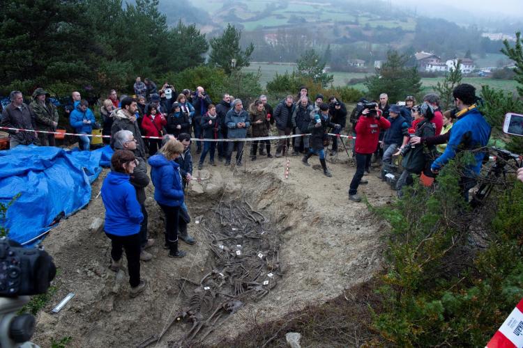 Fotografía de grupo tomada en el lugar donde se ve una fosa con los respectivos huesos