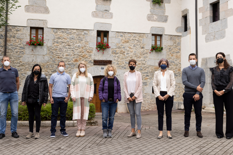 Fotografía de nueve personas delante de una casa de piedra