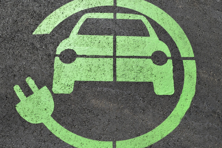 Fotografía de un coche y un enchufe de color verde pintado sobre una superficie negra