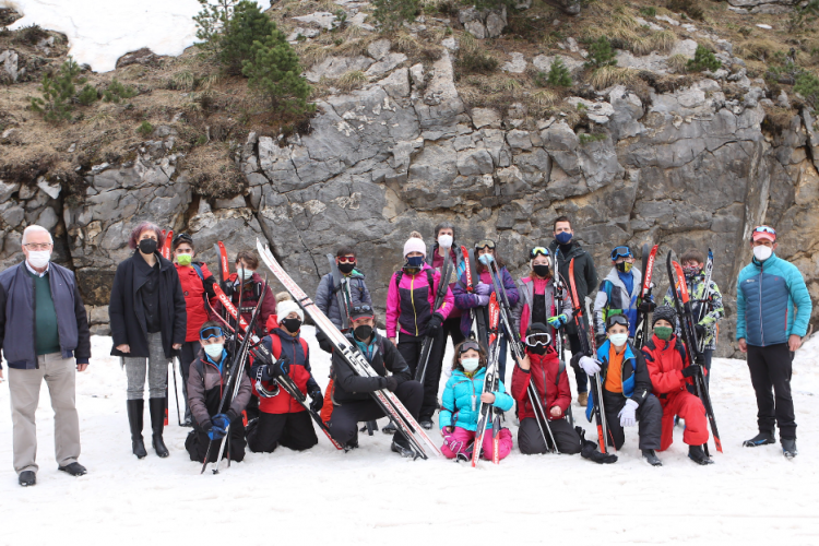 Fotografía en la nieve donde salen cinco adultos y dieciséis niños y niñas con esquís.