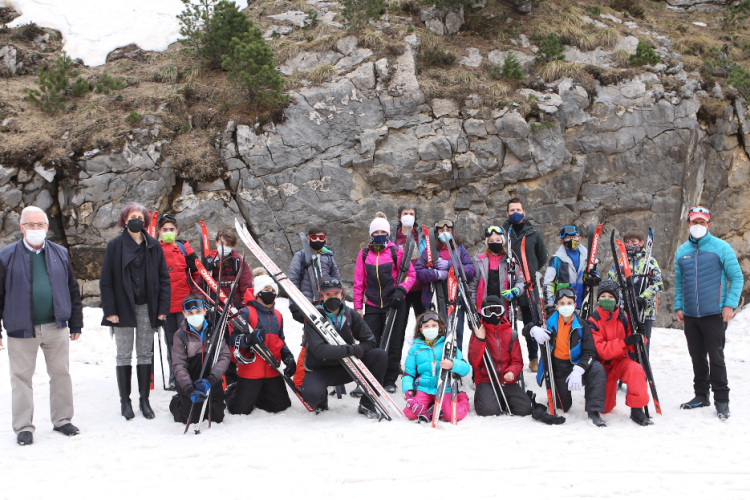 Fotografía en la nieve donde salen cinco adultos y dieciséis niños y niñas con esquís.