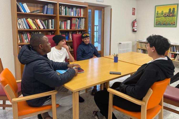 Cuatro jóvenes hablando en una mesa