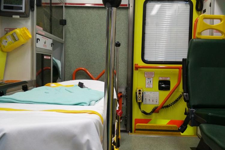 Fotografía del interior de una ambulancia. A mano izquierda se ve una camilla y de fondo una puerta amarilla.