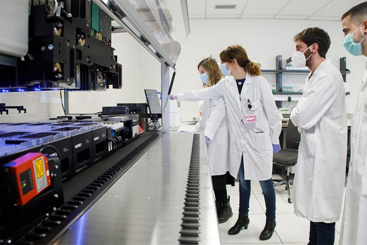 Fotografía interior de un laboratorio con cuatro personas con batas blancas. 