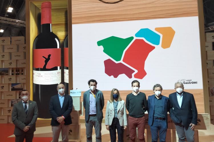 Fotografía de seis hombres y una mujer en una sala con el logotipo del proyecto detrás