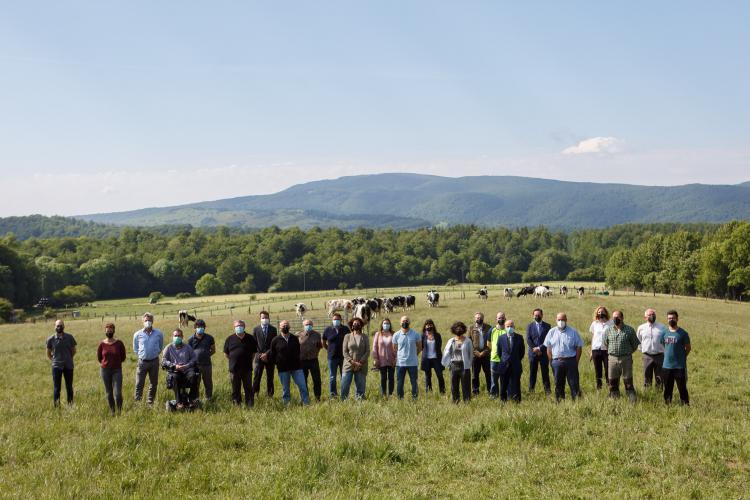 Fotografía de varias personas de pie en un campo con vacas detrás