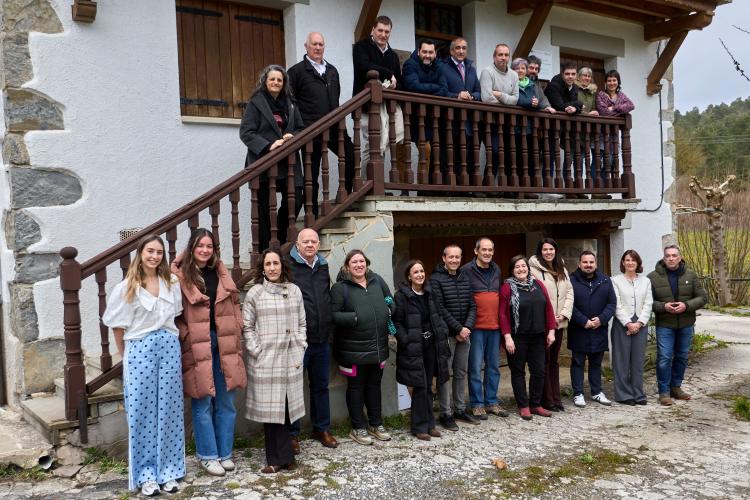Un grupo de personas posando en la fachada de una casa y en sus escaleras