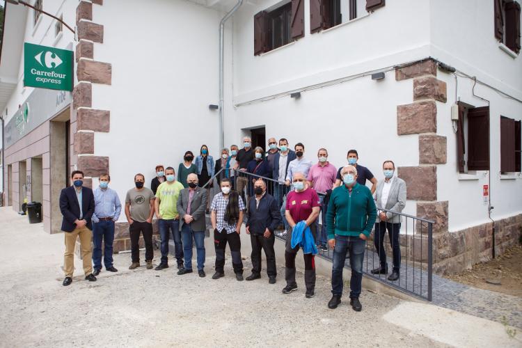 Fotografía exterior de un grupo de personas de pie delante de una casa.