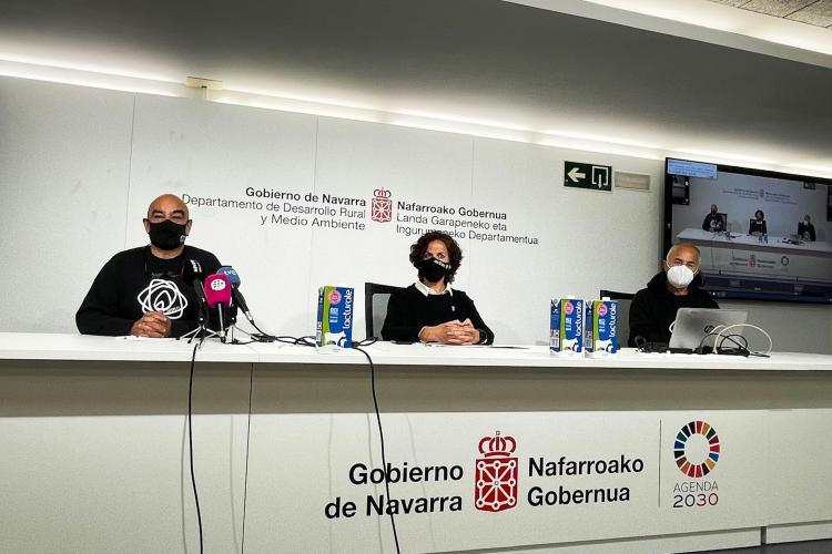 Fotografía de dos hombres y una mujer sentados en una mesa blanca. 