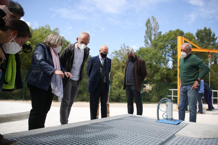 Fotografía de exterior con varias personas de pie observando la depuradora