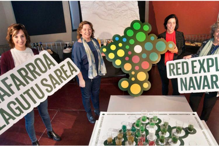 Micaela García, la consejera Isabel Elizalde, Uxue Itoiz y Arantxa Arregui, durante la presentación de la Red Explora Navarra, sobre un mapa formado por zumos elaborados con productos locales de cada comarca.