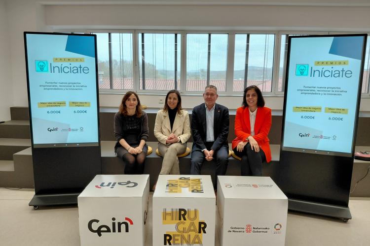 Cuatro personas posando delante de unos cubos con logos